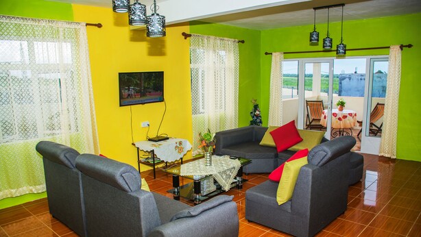 A living room with two grey sofas, a small table with a vase, and a view through a glass door. - Case Latanier (Grand River South East)