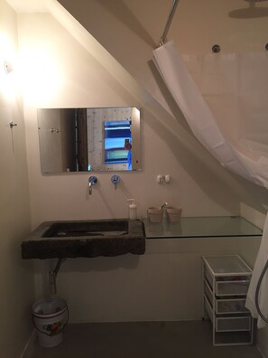 A bathroom with a stone sink, a mirror, a glass shelf, and a shower curtain. - Villino Nacci, in the heart of Tuscany. (San Miniato)