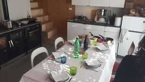 A kitchen with wooden cabinets, a stove, and a dining table set with plates, glasses, and cutlery. - Villino Nacci, in the heart of Tuscany. (San Miniato)