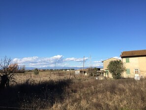 A rural landscape with a single-story building, a clear sky, and distant mountains. - Villino Nacci, in the heart of Tuscany. (San Miniato)