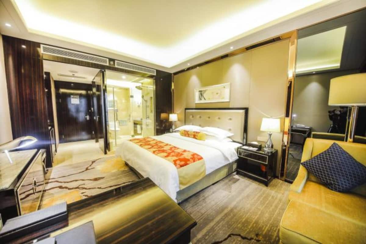 A hotel room with a large bed, a desk, a chair, and a sofa.