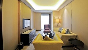 A hotel room with a sofa, armchair, TV, and a lamp. - Tianyue Minshan Hotel (Bazhong)