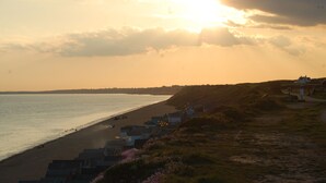 Une plage bordée de cabanes et, au loin, une maison.
