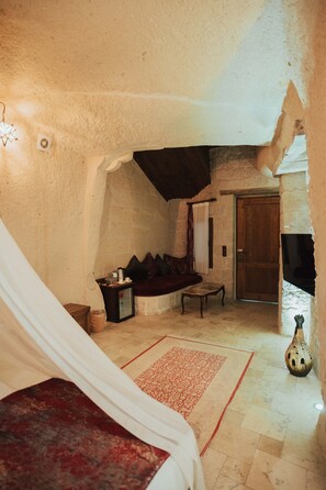 A cozy room with a bed, a sofa, a small table, and a fireplace. - Hu of Cappadocia (Nevsehir)
