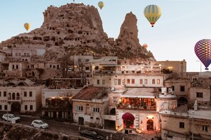 A historic town with traditional architecture, including a prominent rock formation and a brightly lit building with a red awning. - Hu of Cappadocia (Nevsehir)