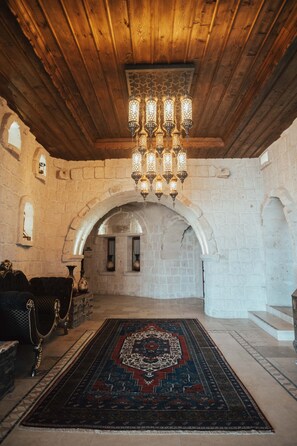 A room with a wooden ceiling, a patterned rug, and a chandelier. - Hu of Cappadocia (Nevsehir)