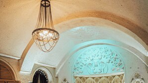 A bedroom with a large bed, a chandelier, and a checkered armchair. - Hu of Cappadocia (Nevsehir)