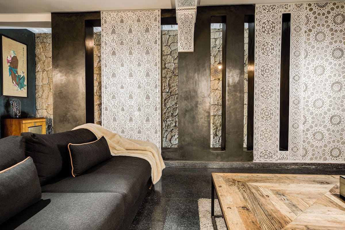 A modern living room with a dark grey sofa, a wooden coffee table, and decorative panels with intricate patterns.