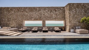 A stone-walled infinity pool with lounge chairs and a view of the sea. - Palais Rhoul Dakhla (Dakhla)