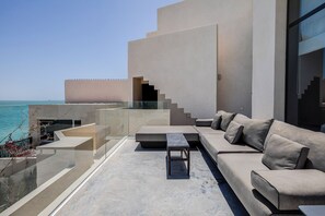 A modern outdoor living space with a sofa, a coffee table, and a staircase leading to an upper level.