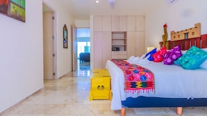 Un dormitorio con cama, ventilador de techo, armario y un pequeño aparador amarillo.
