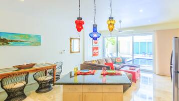 Una cocina moderna con una isla central, comedor con sillas y vistas a una piscina.
