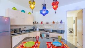 Una cocina moderna con una isla central, electrodomésticos de acero inoxidable y coloridos faroles colgantes.