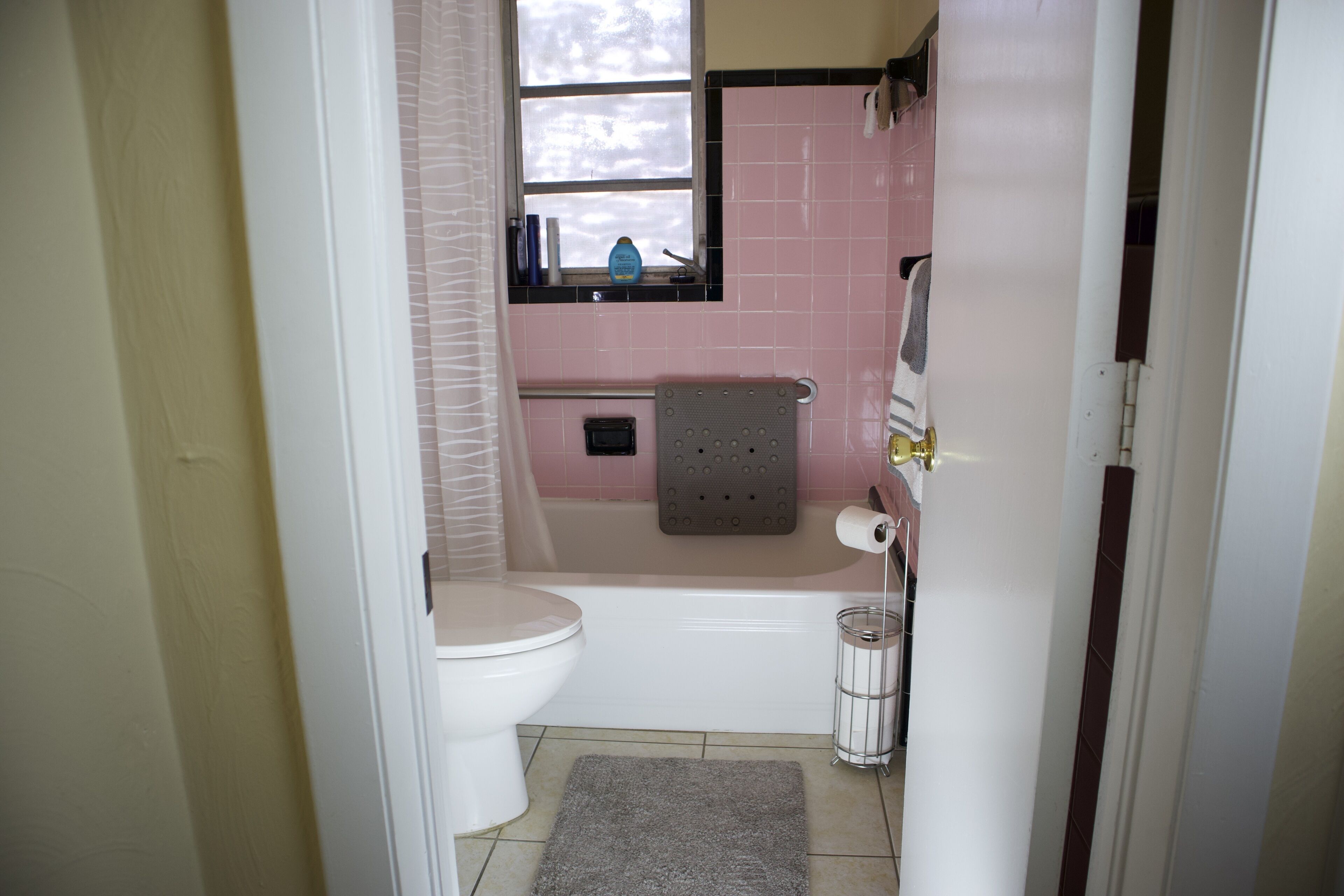 A bathroom with a toilet, bathtub, and a window above the sink.