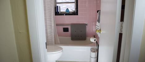A bathroom with a toilet, bathtub, and a window above the sink.