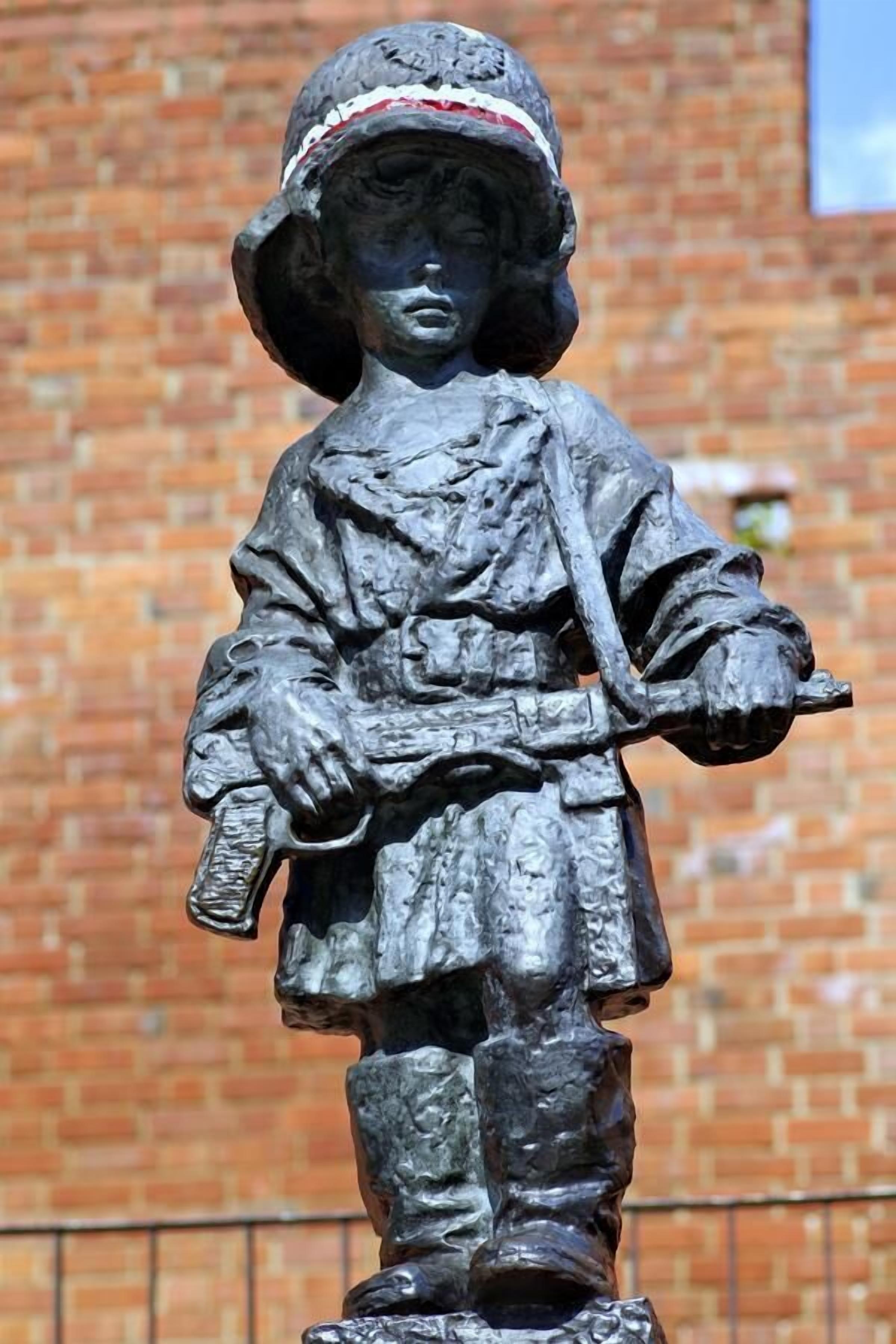A statue of a person wearing a hat and holding a rifle.