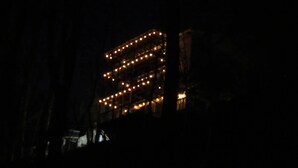 A building with a series of lights arranged in a grid pattern, possibly indicating a hotel or similar establishment.