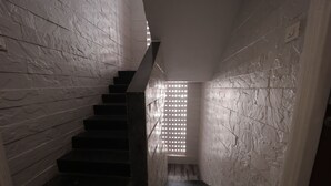 A staircase with a modern design, leading to a room with a patterned wall and a window with a grid pattern. - The Byke Studio Apartment (Thane)
