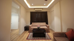 A modern living room with a ceiling fan, a sofa, a coffee table, and a rug. - The Byke Studio Apartment (Thane)