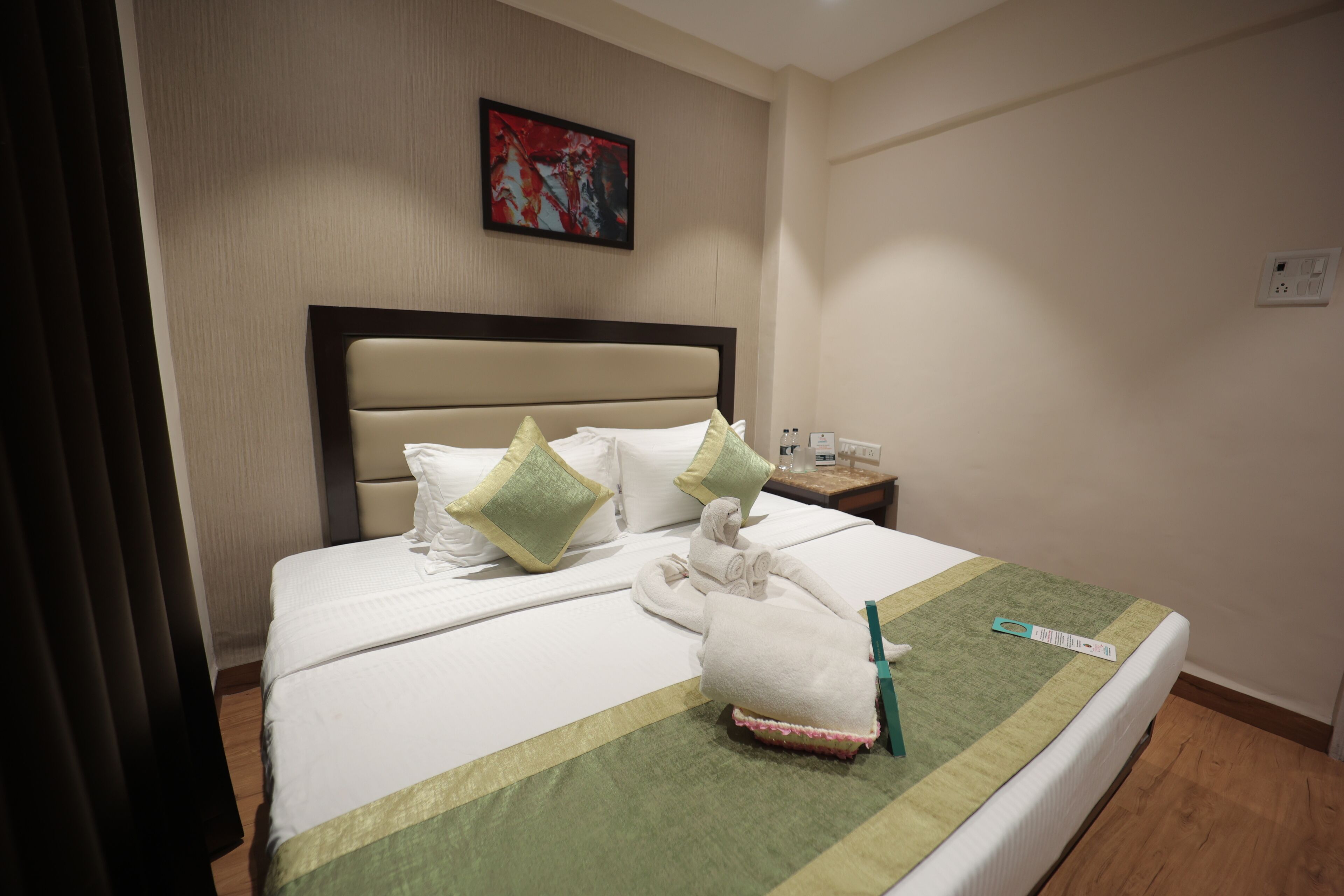 A neatly made bed with a green and white striped bedspread, a headboard, and two pillows.