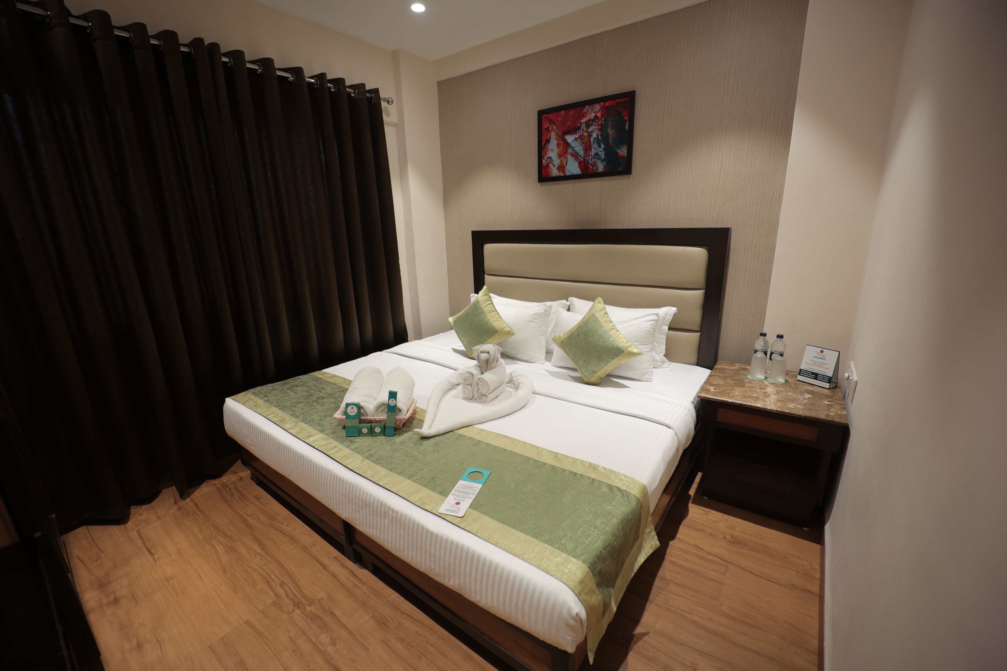 A neatly made bed with pillows, a bedside table with toiletries, and a painting on the wall.