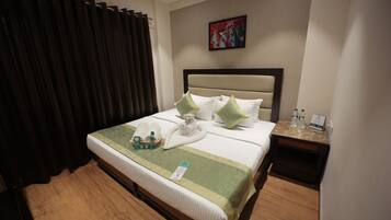 A neatly made bed with pillows, a bedside table with toiletries, and a painting on the wall.
