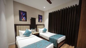 A hotel room with two beds, a wooden floor, a ceiling fan, and artwork on the walls. - The Byke Studio Apartment (Thane)
