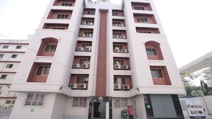 A multi-story hotel with a central entrance, air conditioning units on each floor, and a gated entrance. - The Byke Studio Apartment (Thane)