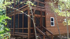 Eine Holzhütte mit einem großen Fenster, einer kleinen Tür und einer Treppe, die zum Eingang führt.