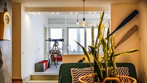 Una sala de estar acogedora con un sofá verde, una mesa de centro de madera y una planta en primer plano.