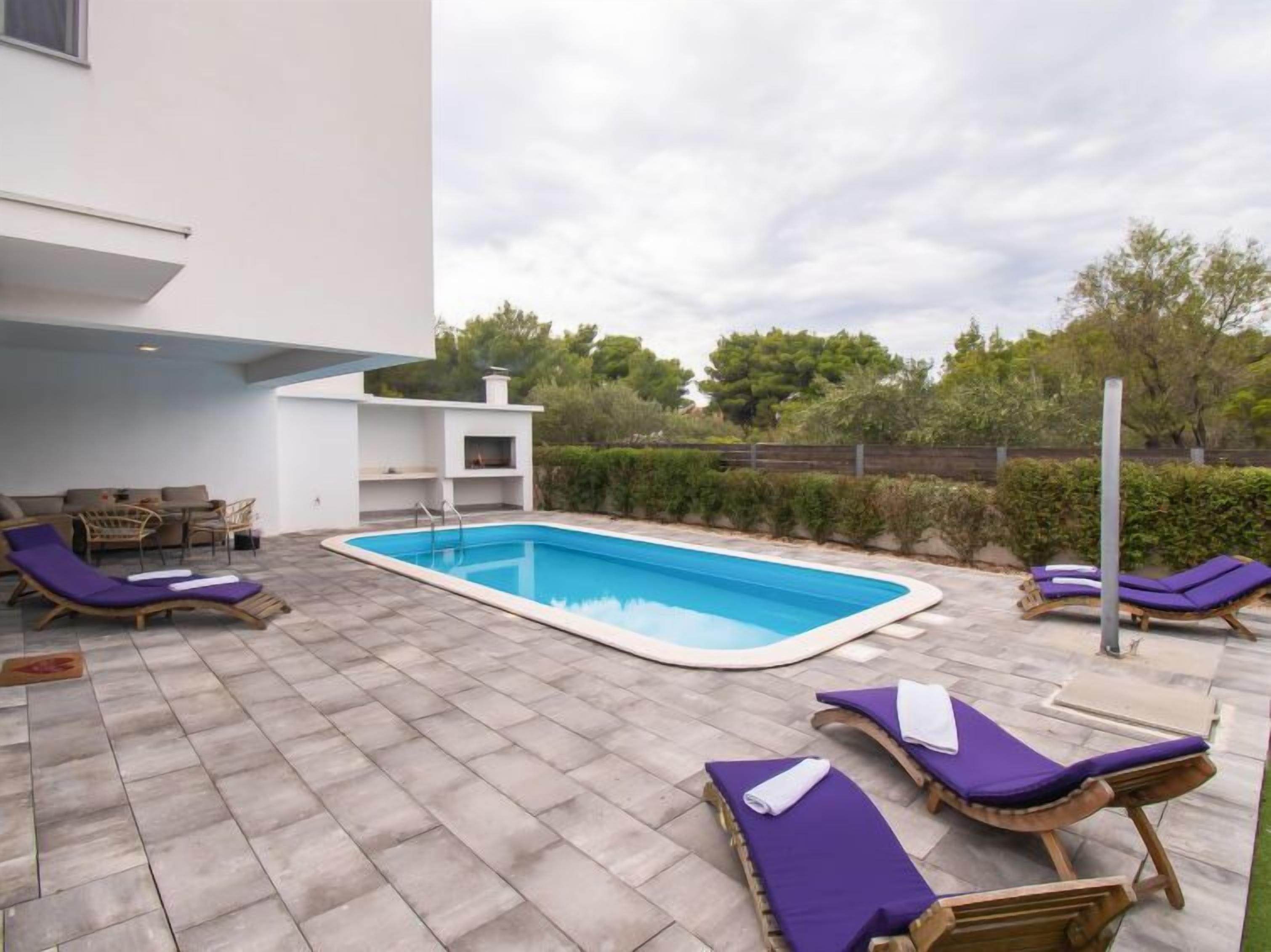 Un espace piscine extérieur moderne, doté de chaises longues et d’un système de divertissement intégré.