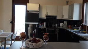 A modern kitchen with a dining area, featuring a refrigerator, oven, sink, and a dining table with chairs.