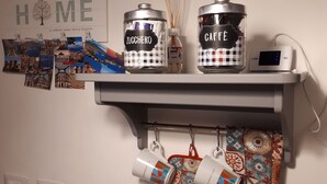 Una cocina con cafetera, hervidor y una cesta de pan.