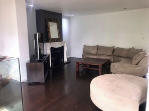 Cozy living space with a fireplace, sofa, armchair, and flat-screen TV.
