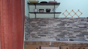 Una cocina con una mesa de madera, un fregadero y estantes con vajilla.