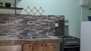 Una cocina con salpicadero de piedra, estufa a gas y pileta.