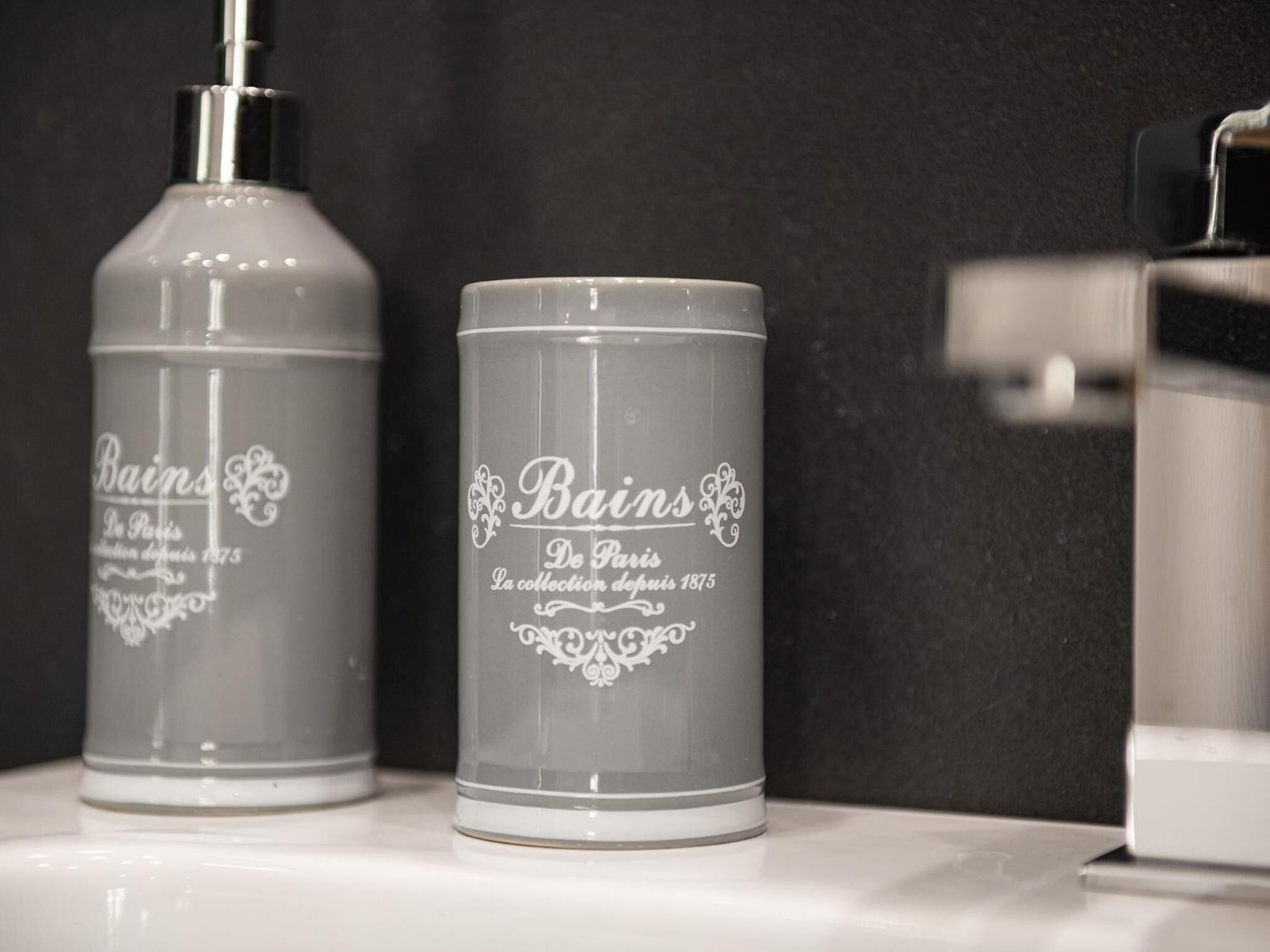 Two gray toiletry bottles with the text "Bains De Paris" on a white surface.