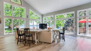 A spacious living room with a large TV, comfortable seating, and a view of the outdoors.