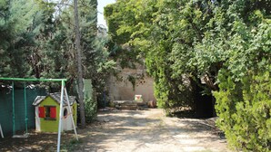 A garden with a swing set, a small playhouse, and a stone wall. - rental house in the Luberon (ROUSSILLON)