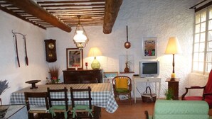 A dining area with a table set for four, a television, and various wall decorations. - rental house in the Luberon (ROUSSILLON)