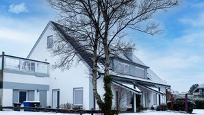 A two-story house with a sloped roof, a visible garage, and a tree in front. - Seeteufel by Interhome (Norddeich)