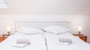 A neatly made twin bed with white linens, two pillows, and two bedside lamps. - Seeteufel by Interhome (Norddeich)