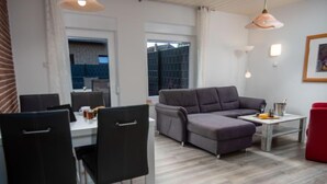 A modern living room with a grey sectional sofa, a dining table with chairs, and a red chair. - Steuerbord by Interhome (Norddeich)