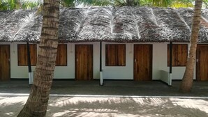 Een rij met rieten hutten met houten deuren, waarschijnlijk onderdeel van een resort of hotel.