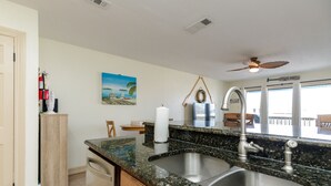 A kitchen with a granite countertop, stainless steel sink, and a ceiling fan.