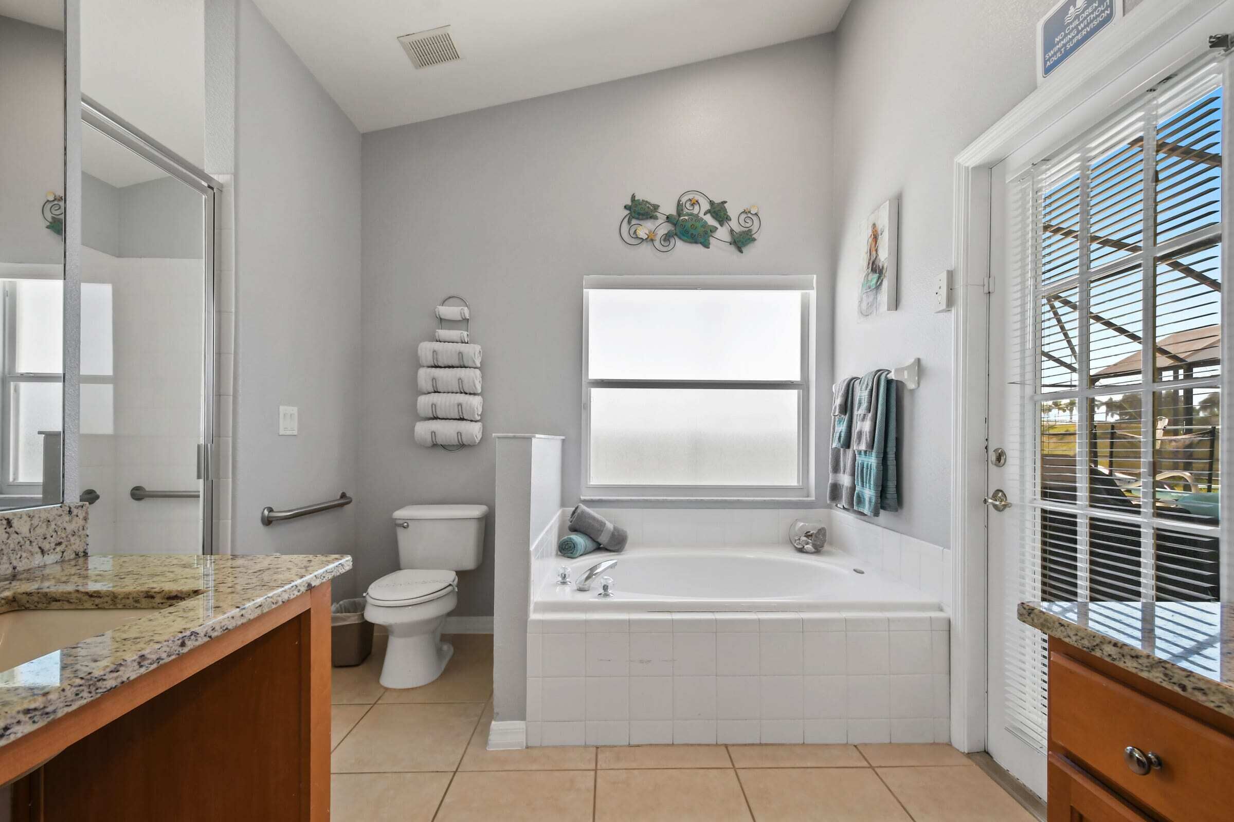 A modern bathroom with a toilet, bathtub, and a vanity with a granite countertop.