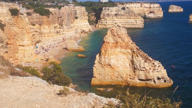 A coastal landscape with rocky cliffs and a beach.