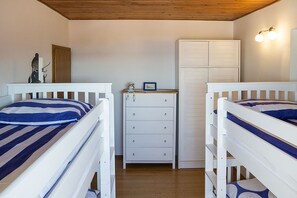 A bedroom with two bunk beds, a dresser, and a wardrobe.