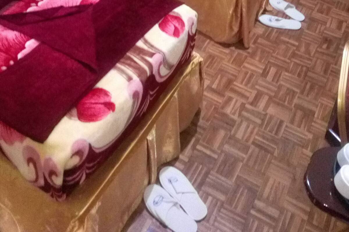 A hotel room with three beds, each with different bedding patterns and colors.