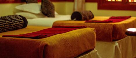 Une chambre avec deux lits, chacun étant recouvert d’une couverture rouge et muni d’un oreiller.
